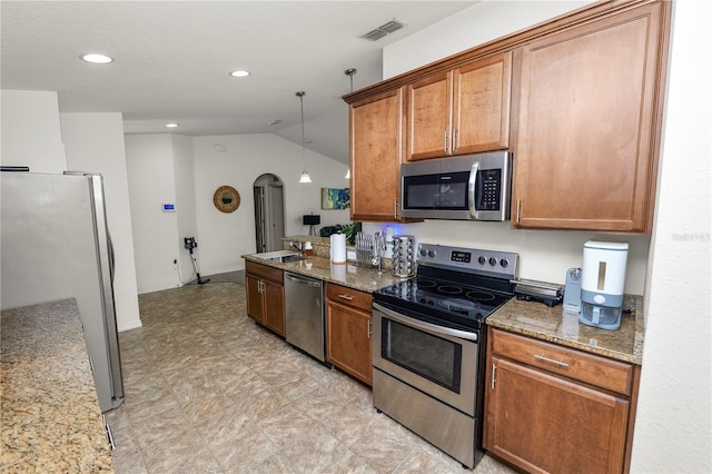 1825 Wallace Manor Ln, Winter Haven, FL 33880 - kitchen with stainless steel appliances, vaulted ceiling, brown cabinetry, stone countertops, and arched walkways