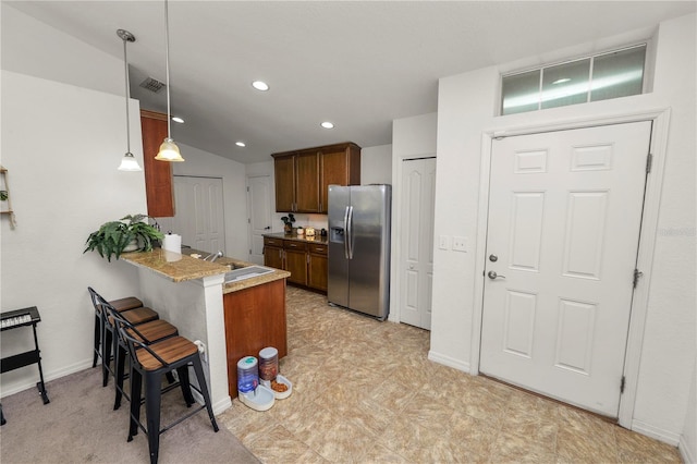 1825 Wallace Manor Ln, Winter Haven, FL 33880 - kitchen featuring stainless steel fridge with ice dispenser, a peninsula, a breakfast bar, hanging light fixtures, and a sink