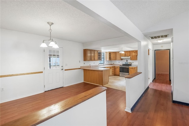 120 Bolender Rd, Auburndale, FL 33823 - kitchen with stainless steel electric range oven, wood finished floors, under cabinet range hood, a textured ceiling, and a peninsula