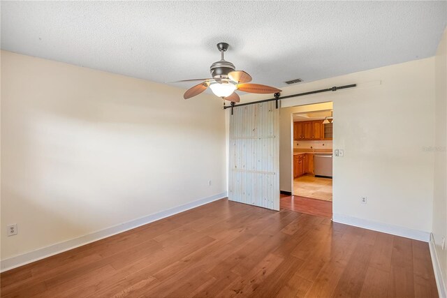 120 Bolender Rd, Auburndale, FL 33823 - unfurnished room featuring a barn door, wood finished floors, a ceiling fan, baseboards, and a textured ceiling
