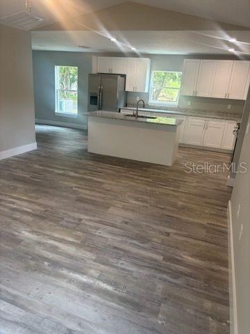 kitchen with stainless steel refrigerator with ice dispenser, a sink, and dark wood-style flooring