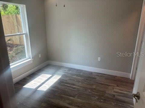 spare room featuring baseboards and wood finished floors