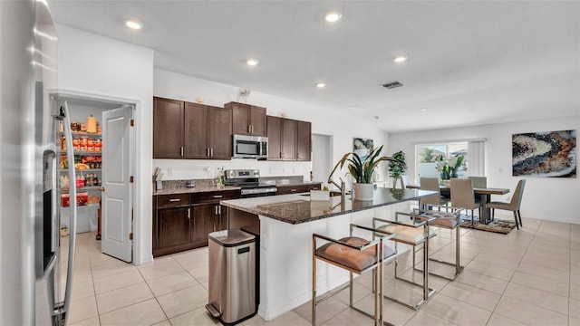 2991 Flying Blackbird Rd, Bartow, FL 33830 - kitchen featuring stainless steel appliances, a kitchen bar, recessed lighting, a center island with sink, and dark stone countertops