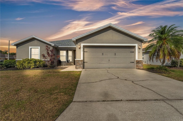 ranch-style home featuring stucco siding, stone siding, concrete driveway, and a front lawn