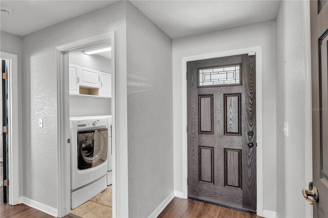 washroom featuring washer / clothes dryer, a textured wall, baseboards, and wood finished floors