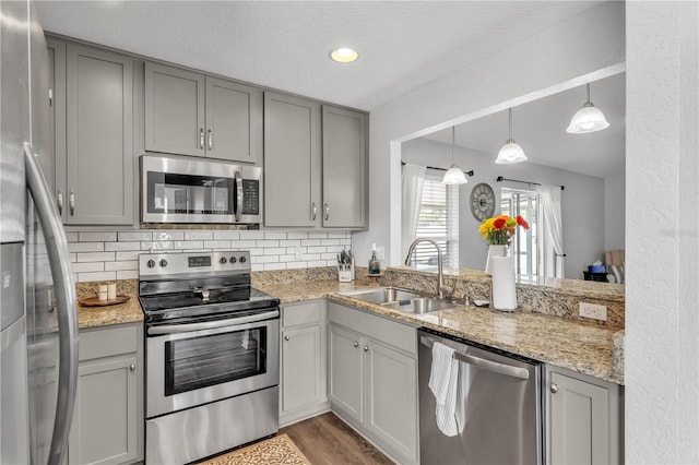 kitchen featuring appliances with stainless steel finishes, gray cabinetry, a sink, backsplash, and a textured ceiling
