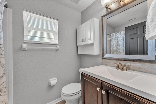 bathroom featuring toilet, a textured wall, vanity, curtained shower, and tasteful backsplash