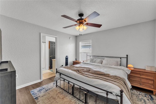 bedroom featuring a textured ceiling, wood finished floors, a textured wall, baseboards, and a ceiling fan