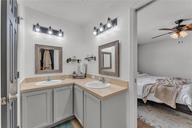 ensuite bathroom with ceiling fan, double vanity, and wood finished floors