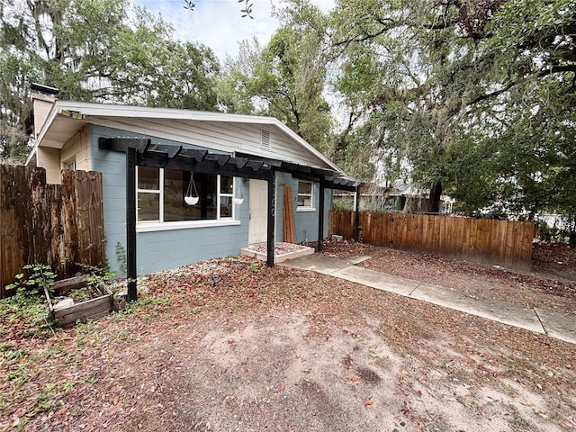 bungalow with fence, concrete block siding, and a chimney