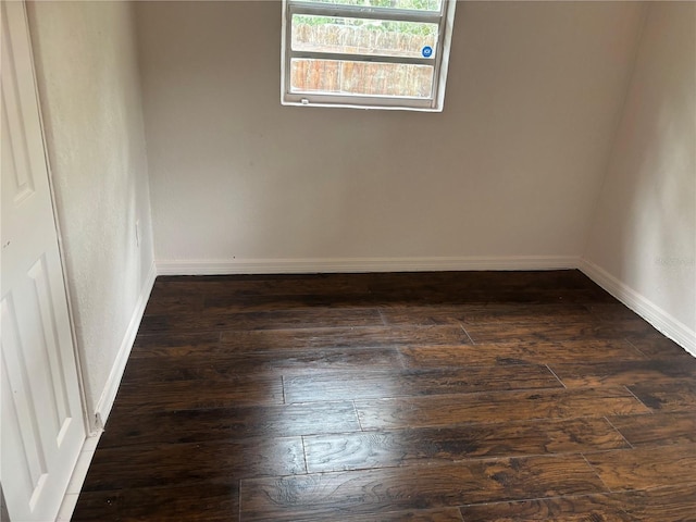 empty room featuring dark wood-style floors and baseboards