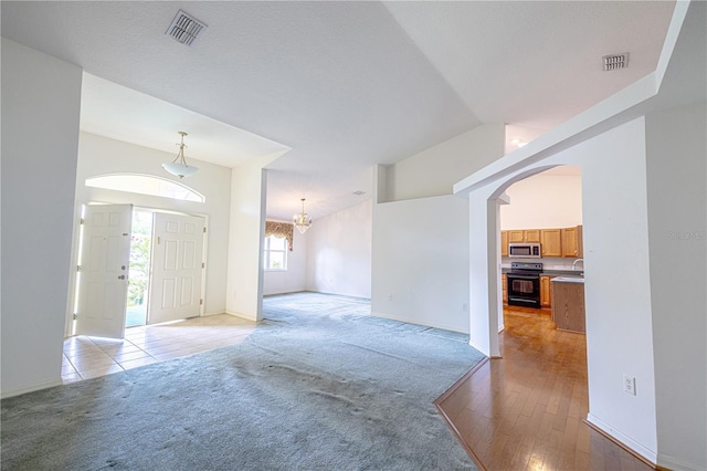 3798 N Chandler Dr, Hernando, FL 34442 - unfurnished living room with light colored carpet, arched walkways, baseboards, and a chandelier