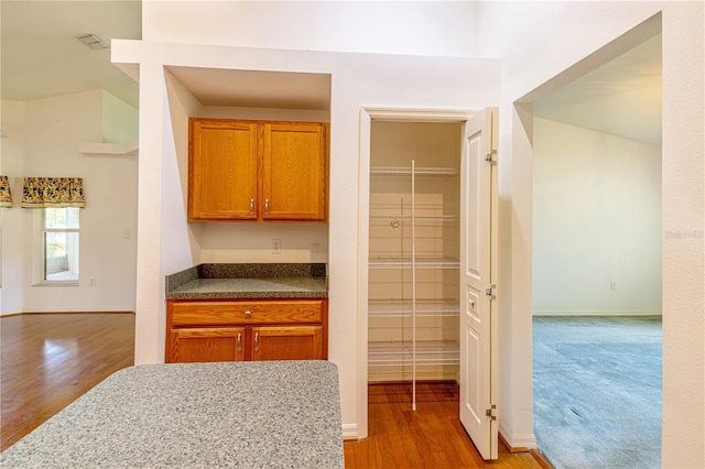 3798 N Chandler Dr, Hernando, FL 34442 - kitchen with wood finished floors, brown cabinetry, baseboards, and dark countertops
