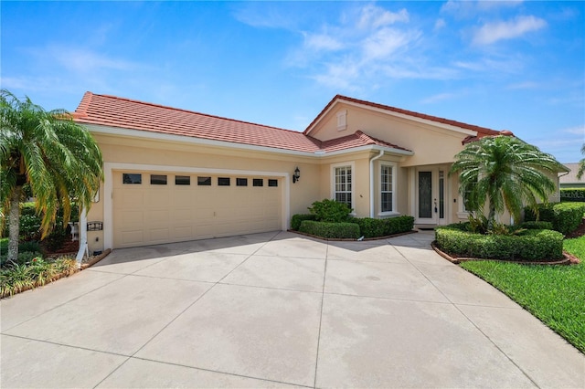 mediterranean / spanish-style home featuring a tile roof, driveway, stucco siding, and an attached garage