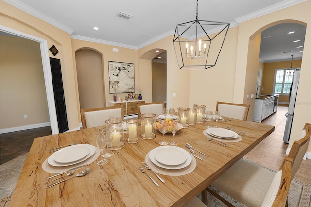 dining space featuring arched walkways, crown molding, baseboards, recessed lighting, and a chandelier