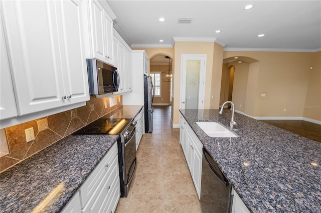 kitchen with stainless steel appliances, a sink, arched walkways, ornamental molding, and tasteful backsplash