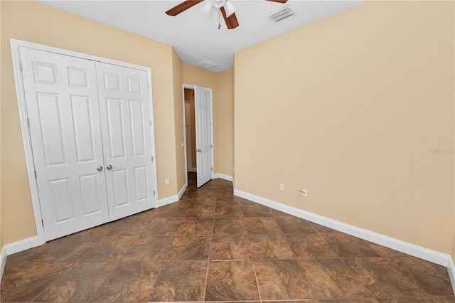 unfurnished bedroom featuring a closet, baseboards, ceiling fan, and stone finish floors