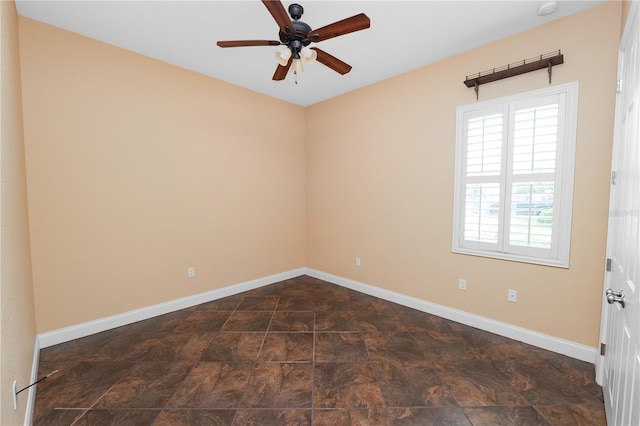 unfurnished room featuring ceiling fan, baseboards, and dark stone finish floors