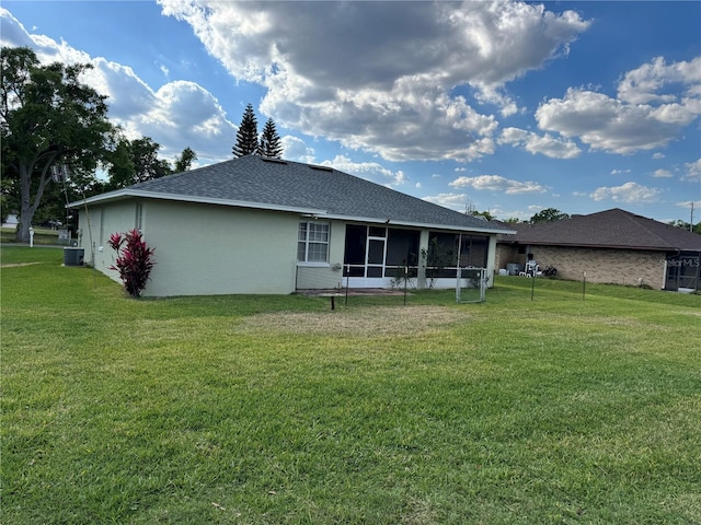 200 S Goodman Ave, Lake Alfred, FL 33850 - rear view of house with a lawn, a sunroom, roof with shingles, central AC unit, and stucco siding