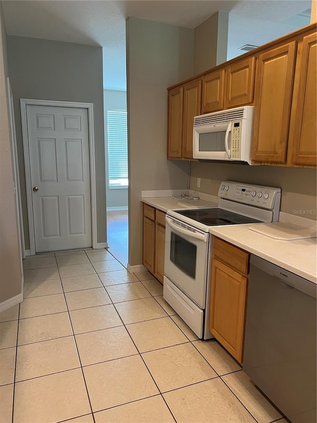 200 S Goodman Ave, Lake Alfred, FL 33850 - kitchen with white appliances, light tile patterned floors, light countertops, and baseboards