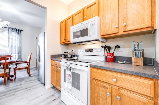 3281 Enclave Blvd, Mulberry, FL 33860 - kitchen featuring white appliances, dark countertops, and light wood-style flooring