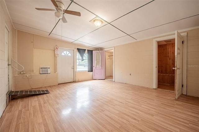 unfurnished room featuring light wood-style flooring, concrete block wall, and ceiling fan