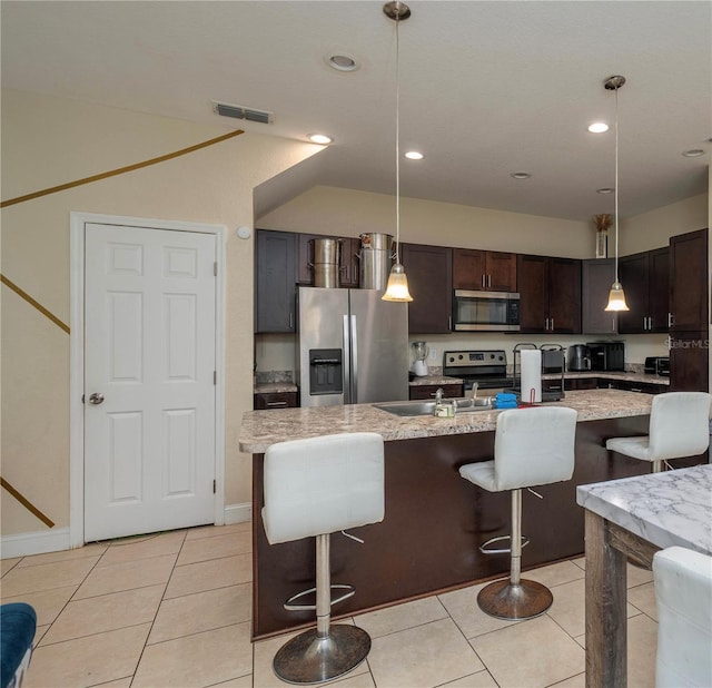 1105 Watersedge Dr, Lakeland, FL 33801 - kitchen featuring appliances with stainless steel finishes, a breakfast bar, dark brown cabinetry, light tile patterned floors, and recessed lighting