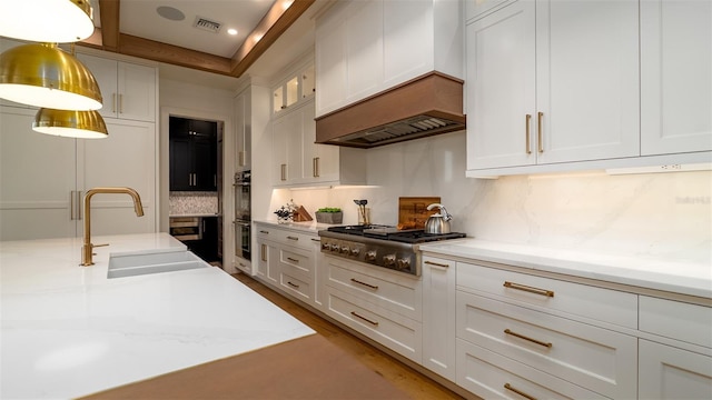 531 68th St, Holmes Beach, FL 34217 - kitchen featuring stainless steel gas stovetop, a sink, white cabinetry, decorative backsplash, and hanging light fixtures