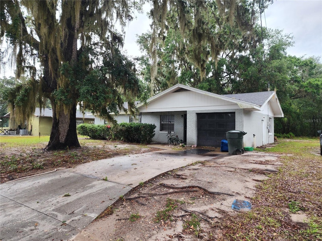 view of property exterior with asphalt driveway, an attached garage, and brick siding