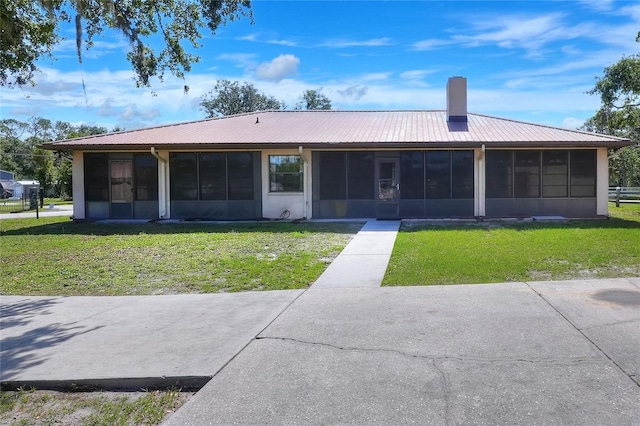 4404 Musket Dr, Lakeland, FL 33810 - rear view of property with a sunroom, a chimney, a lawn, and metal roof