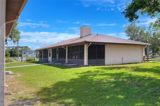 4404 Musket Dr, Lakeland, FL 33810 - back of house featuring a chimney, a sunroom, a lawn, and stucco siding