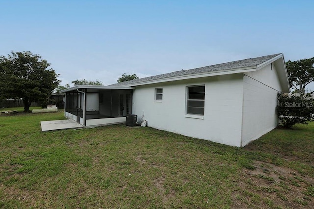 rear view of property featuring a sunroom, a yard, and central AC