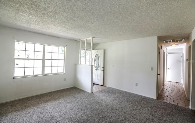 spare room featuring carpet, a textured ceiling, and baseboards