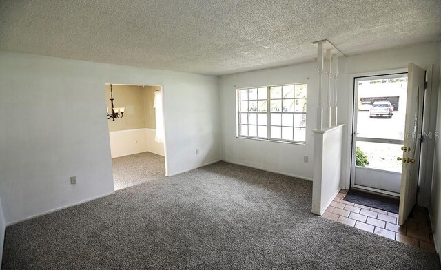 carpeted foyer entrance with plenty of natural light, a chandelier, and a textured ceiling
