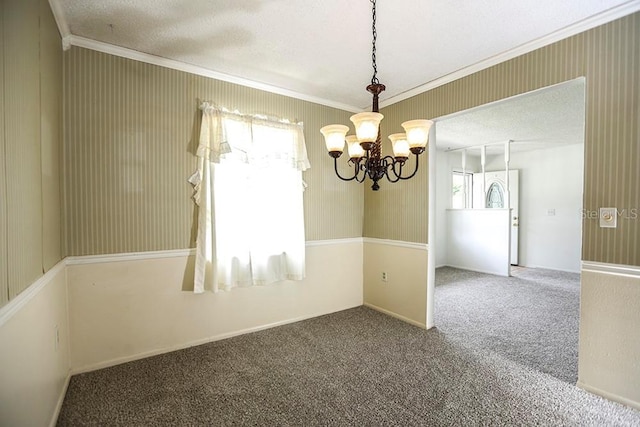 carpeted spare room with a chandelier, ornamental molding, and a textured ceiling