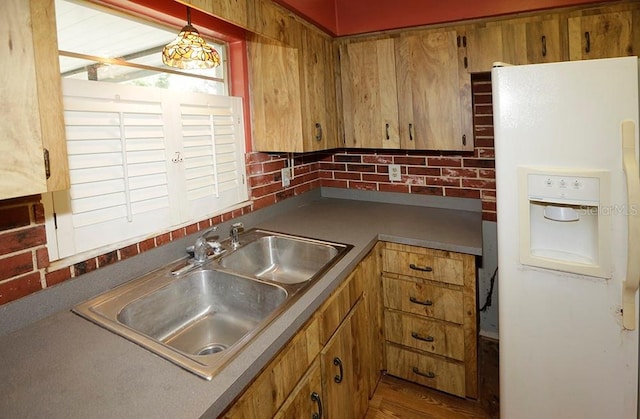 kitchen with white fridge with ice dispenser, a sink, brown cabinetry, and decorative light fixtures