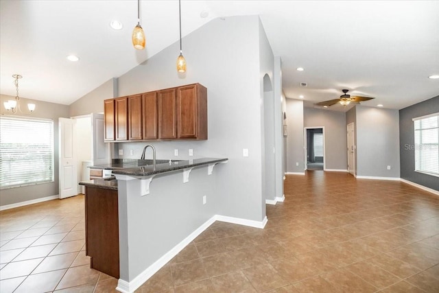 12654 Belcroft Dr, Riverview, FL 33579 - kitchen with vaulted ceiling, light tile patterned floors, a peninsula, brown cabinets, and a kitchen bar