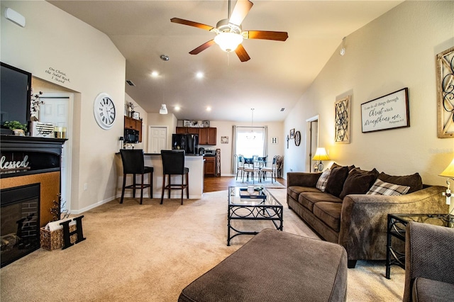 living area with lofted ceiling, a fireplace, ceiling fan, light colored carpet, and baseboards