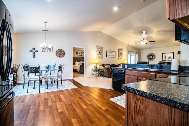 kitchen with black appliances, a chandelier, ceiling fan, dark countertops, and light wood finished floors