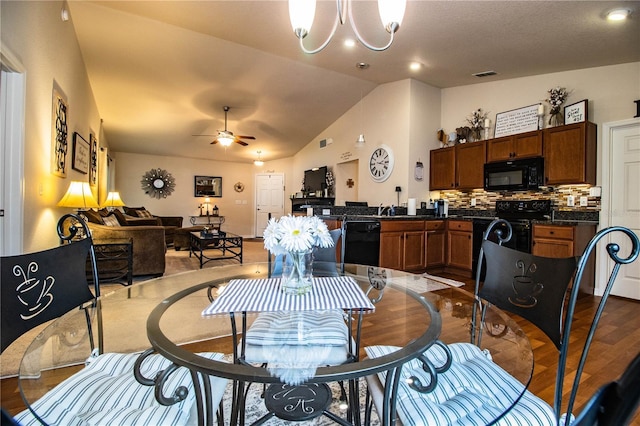 dining room featuring lofted ceiling, wood finished floors, a ceiling fan, and a chandelier