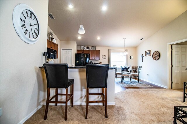 kitchen with black appliances, carpet flooring, a breakfast bar, dark countertops, and recessed lighting