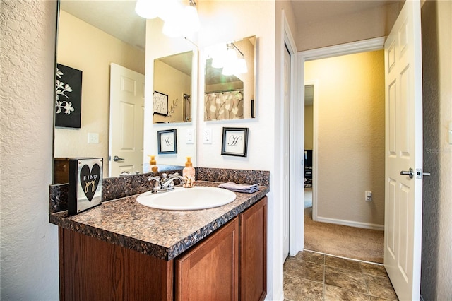 bathroom featuring a textured wall, vanity, and baseboards