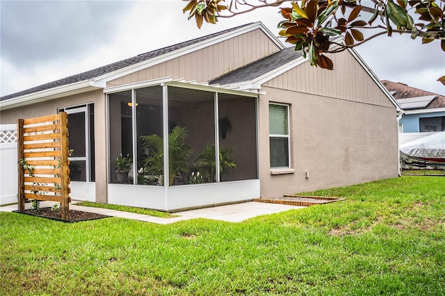 view of property exterior featuring a sunroom, roof with shingles, and a yard