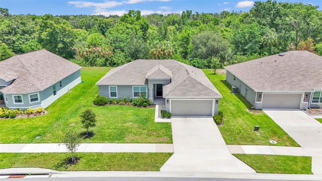 4582 Penkert Pl, Lakeland, FL 33811 - view of front of home with concrete driveway, a front lawn, stucco siding, an attached garage, and a forest view