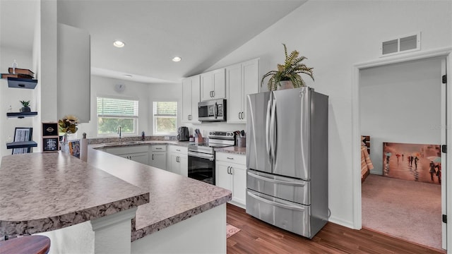 4582 Penkert Pl, Lakeland, FL 33811 - kitchen with appliances with stainless steel finishes, a peninsula, a sink, white cabinets, and vaulted ceiling
