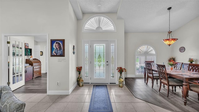 2912 Aston Ave, Plant City, FL 33566 - foyer with healthy amount of natural light, a towering ceiling, a textured ceiling, light tile patterned flooring, and baseboards