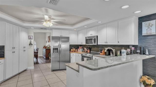2912 Aston Ave, Plant City, FL 33566 - kitchen with appliances with stainless steel finishes, a tray ceiling, light tile patterned flooring, ceiling fan, and white cabinets