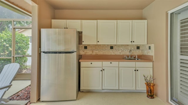 2912 Aston Ave, Plant City, FL 33566 - kitchen featuring freestanding refrigerator, a sink, decorative backsplash, light countertops, and white cabinetry