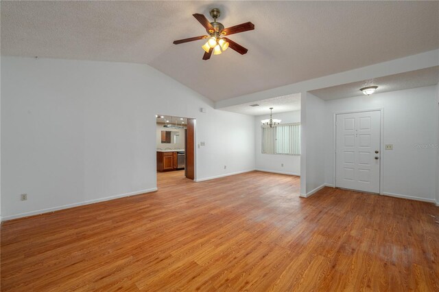 409 San Jose Dr, Winter Haven, FL 33884 - unfurnished living room with a chandelier, ceiling fan, light wood finished floors, lofted ceiling, and baseboards