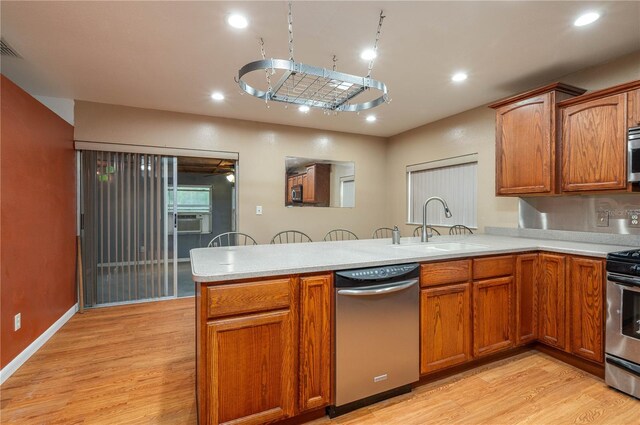 409 San Jose Dr, Winter Haven, FL 33884 - kitchen featuring stainless steel appliances, a peninsula, light wood-type flooring, light countertops, and a sink